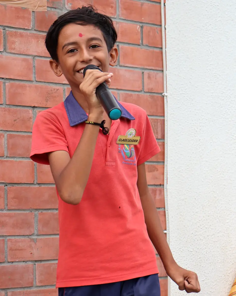A smiling Rainbow English School student speaking at a school event